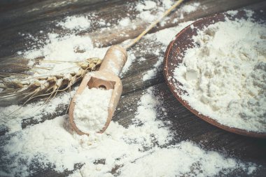 Ekmek pişirmek için un ve buğday başakları ahşap bir yüzeyde yatar.