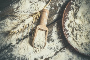 Ekmek pişirmek için un ve buğday başakları ahşap bir yüzeyde yatar.