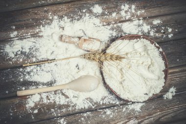 Ekmek pişirmek için un ve buğday başakları ahşap bir yüzeyde yatar.