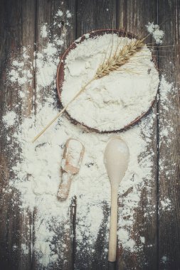 Ekmek pişirmek için un ve buğday başakları ahşap bir yüzeyde yatar.