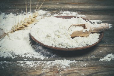 Ekmek pişirmek için un ve buğday başakları ahşap bir yüzeyde yatar.