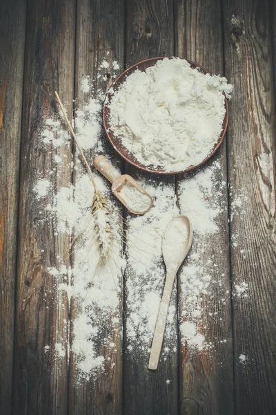 Flour and spikelets of wheat for baking bread lies on a wooden surface