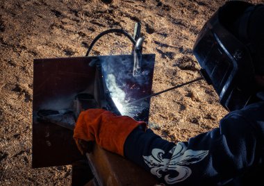 Maskeli kaynakçı inşaat alanında metal kaynaklıyor.