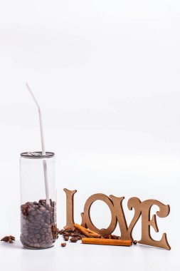 Beyaz arka planda plastik kavanozdaki kahve çekirdekleri.