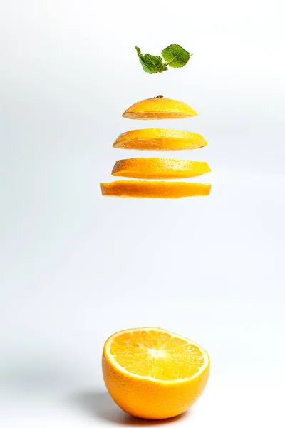 Sliced orange and half an orange on a white background in hand