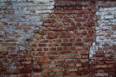 Üzerinde çizikler ve aşınma olan eski kırmızı tuğla bir duvar..