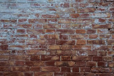 Üzerinde çizikler ve aşınma olan eski kırmızı tuğla bir duvar..