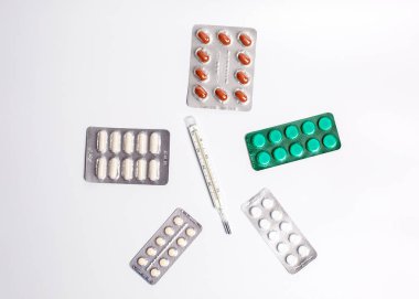 Vücut ısısını ölçmek için termometre ve hastalığı tedavi etmek için birçok farklı hap.