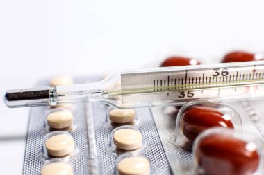 Vücut ısısını ölçmek için termometre ve hastalığı tedavi etmek için birçok farklı hap.