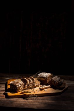 Güzel kokulu, taze ve lezzetli siyah ekmek, dikenleri ve tahılları olan eski bir yüzey.