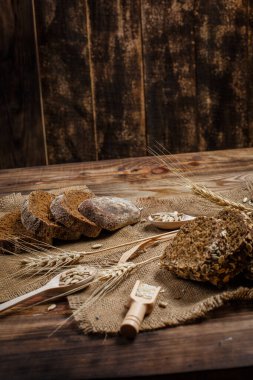 Baharatlı mis kokulu ve lezzetli siyah ekmek eski bir yüzey üzerinde dikenlerin ve tohumların yanında yatar.