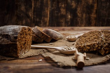 Baharatlı mis kokulu ve lezzetli siyah ekmek eski bir yüzey üzerinde dikenlerin ve tohumların yanında yatar.