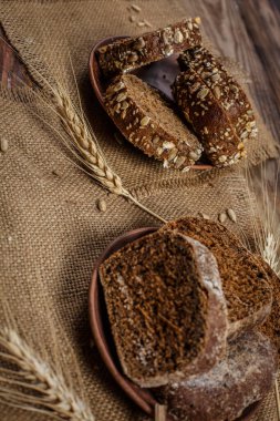 Güzel kokulu, taze ve lezzetli siyah ekmek, dikenleri ve tahılları olan eski bir yüzey.