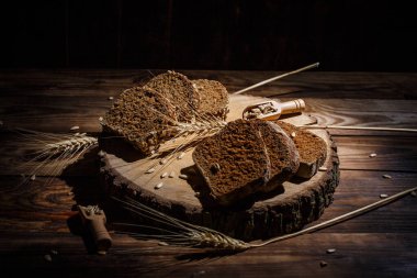 Baharatlı mis kokulu ve lezzetli siyah ekmek eski bir yüzey üzerinde dikenlerin ve tohumların yanında yatar.