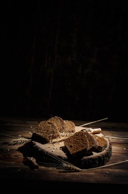 Baharatlı mis kokulu ve lezzetli siyah ekmek eski bir yüzey üzerinde dikenlerin ve tohumların yanında yatar.