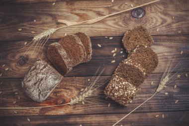 Baharatlı mis kokulu ve lezzetli siyah ekmek eski bir yüzey üzerinde dikenlerin ve tohumların yanında yatar.