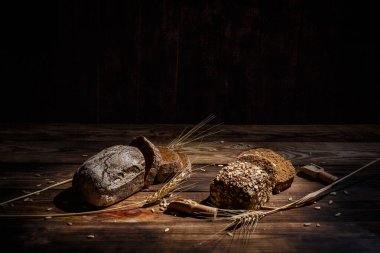 Baharatlı mis kokulu ve lezzetli siyah ekmek eski bir yüzey üzerinde dikenlerin ve tohumların yanında yatar.