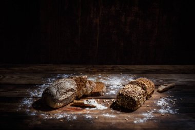 Baharatlı mis kokulu ve lezzetli siyah ekmek eski bir yüzey üzerinde dikenlerin ve tohumların yanında yatar.