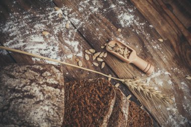 Baharatlı mis kokulu ve lezzetli siyah ekmek eski bir yüzey üzerinde dikenlerin ve tohumların yanında yatar.