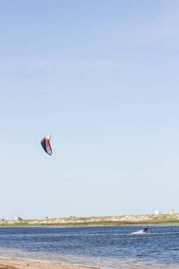 Atlet, sıcak yaz mevsiminde atlayışlar ve hilelerle denizde uçurtma sürüyor..