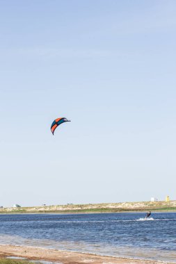 Atlet, sıcak yaz mevsiminde atlayışlar ve hilelerle denizde uçurtma sürüyor..