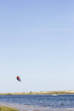Atlet, sıcak yaz mevsiminde atlayışlar ve hilelerle denizde uçurtma sürüyor..