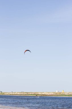 Atlet, sıcak yaz mevsiminde atlayışlar ve hilelerle denizde uçurtma sürüyor..