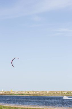 Atlet, sıcak yaz mevsiminde atlayışlar ve hilelerle denizde uçurtma sürüyor..