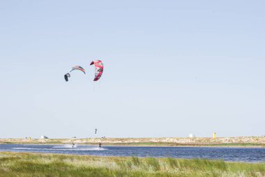 Atlet, sıcak yaz mevsiminde atlayışlar ve hilelerle denizde uçurtma sürüyor..