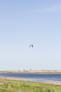 Atlet, sıcak yaz mevsiminde atlayışlar ve hilelerle denizde uçurtma sürüyor..