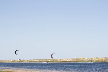 Atlet, sıcak yaz mevsiminde atlayışlar ve hilelerle denizde uçurtma sürüyor..