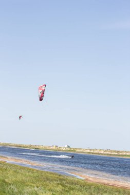 Atlet, sıcak yaz mevsiminde atlayışlar ve hilelerle denizde uçurtma sürüyor..