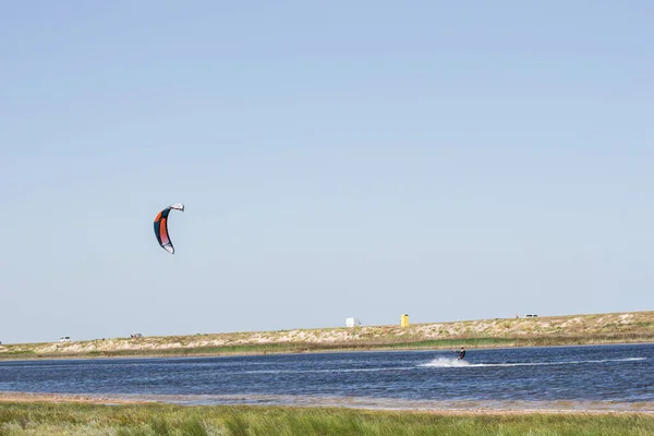 選手はジャンプやトリックで暑い夏に海でカイトサーフィンに乗る — ストック写真