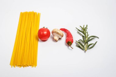 Çiğ makarna, taze sebzeler, domatesler ve mantarlar kapalı beyaz bir tabakta.