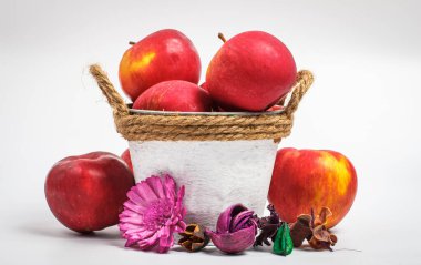 Beyaz arka planda güzel kırmızı elmalar güzel çiçekler ve beyaz bir kovada