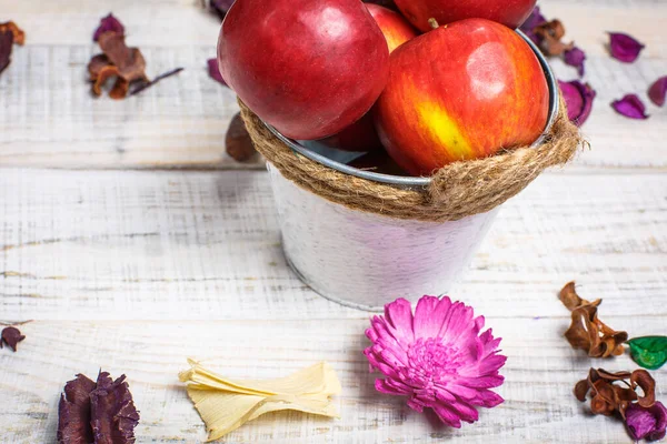 Beautiful red sweet apples on a white background with beautiful flowers and in a white bucket