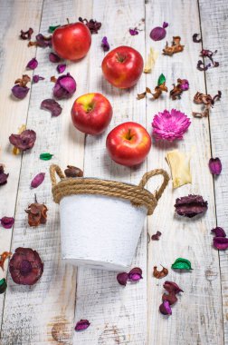 Beyaz arka planda güzel kırmızı elmalar güzel çiçekler ve beyaz bir kovada