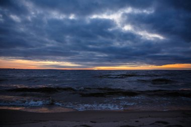 Kışın dalgalı geniş bir nehrin üzerinde gün batımı