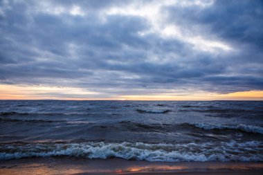 Kışın dalgalı geniş bir nehrin üzerinde gün batımı