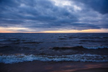 Kışın dalgalı geniş bir nehrin üzerinde gün batımı