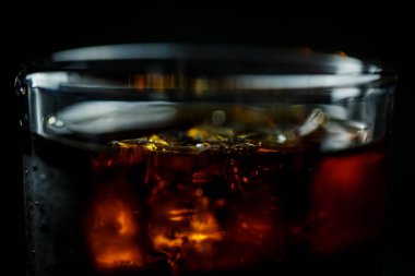 Siyah arka planda, buzlu ve damlacıklı bir bardakta soda.