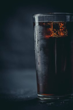 Siyah arka planda, buzlu ve damlacıklı bir bardakta soda.