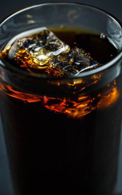 Siyah arka planda, buzlu ve damlacıklı bir bardakta soda.