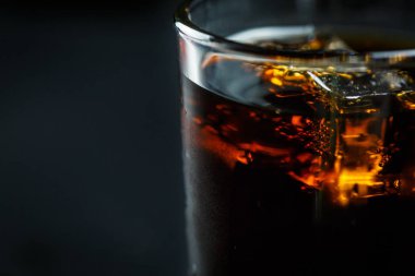 Siyah arka planda, buzlu ve damlacıklı bir bardakta soda.