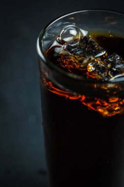 Siyah arka planda, buzlu ve damlacıklı bir bardakta soda.