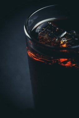 Siyah arka planda, buzlu ve damlacıklı bir bardakta soda.