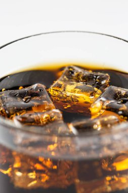 Beyaz arka planda buzlu bardakta siyah soda.