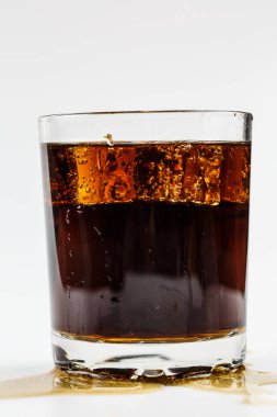 Beyaz arka planda buzlu bardakta siyah soda.