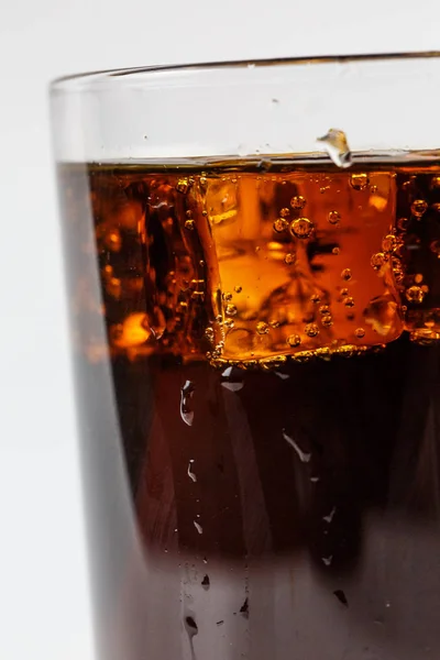 Black soda in a glass with ice on a white background