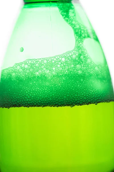 Beer with bubbles and foam in a green bottle